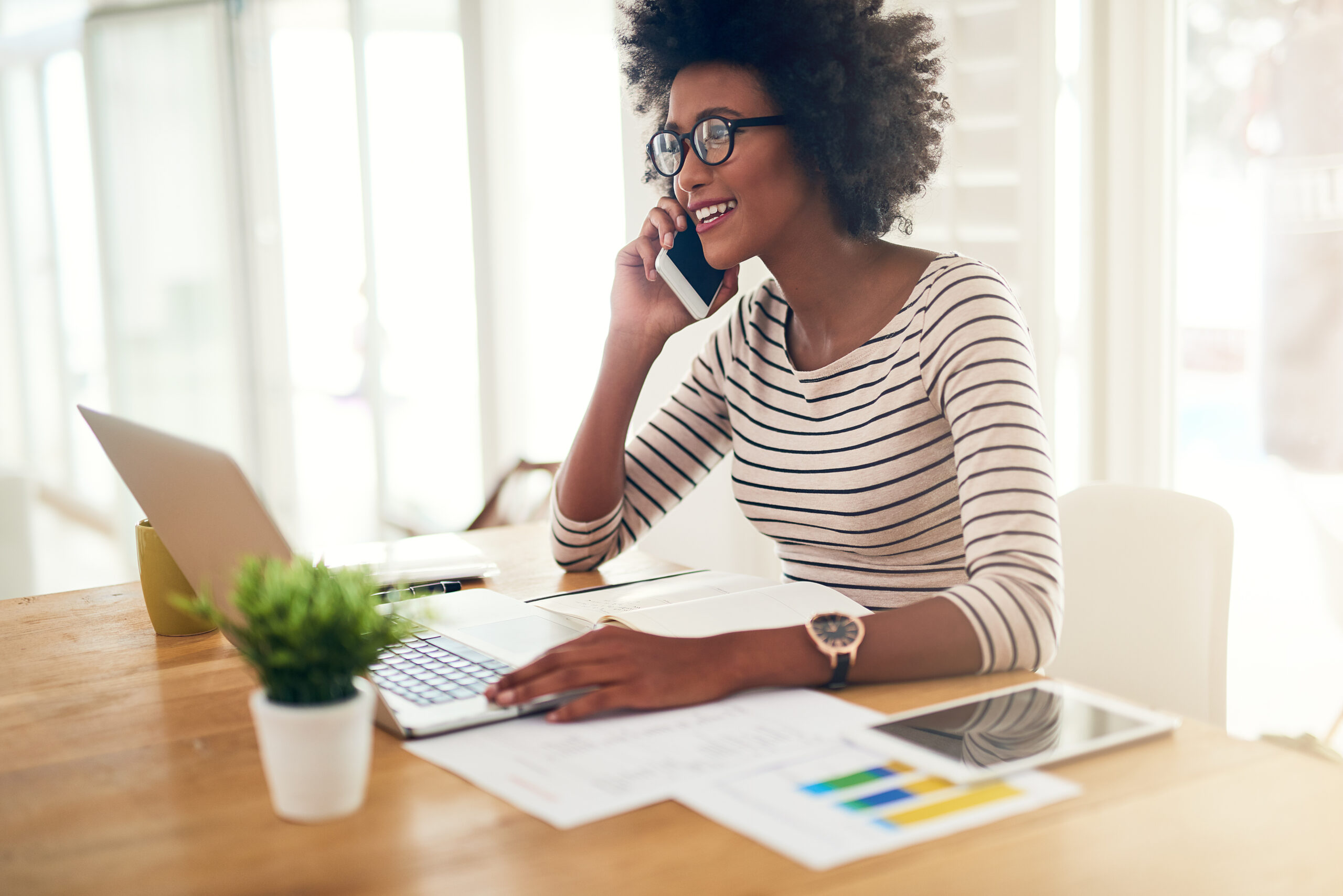 Phone call, laptop and black woman accountant talking financial company or startup strategy in home office. Cellphone, happy and entrepreneur or employee planning graph results doing remote work.